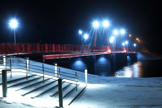 Night landscape with nice red bridge across river in winter at night