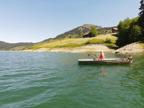 woman with long blond hair on boat with roses and flowers on blue lake