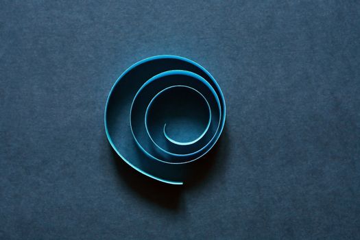 Blue spiral made from paper on dark background