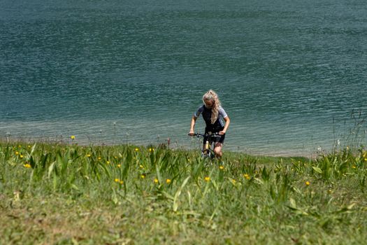 Life style woman with long blond hair on mountain bike in Swiss Alps