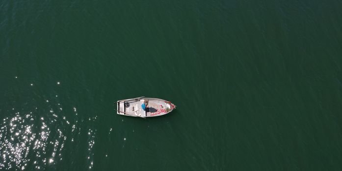 woman with long blond hair on boat with roses and flowers on blue lake