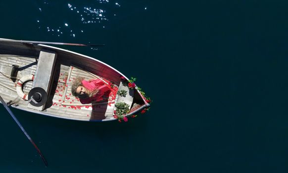 woman with long blond hair on boat with roses and flowers on blue