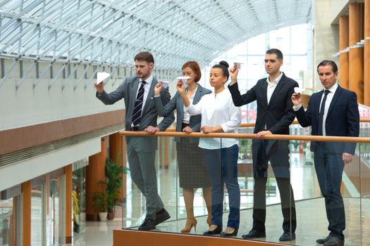 Team of business people throwing together paper planes in modern office building