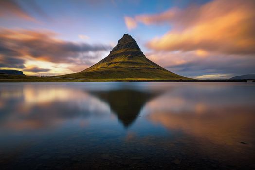 Summer sunset over the famous Kirkjufell mountain with reflection in a nearby lake in Iceland. Long exposure.