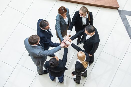 Business teamwork concept, coworkers putting hands together in a tower stacking hands unity cooperation concept, top view