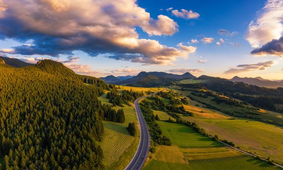 Aerial view of a road going through forests of the Liptov region in Slovakia at sunset.