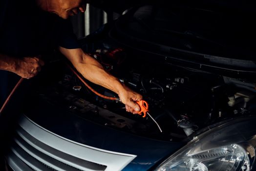 Car mechanic or serviceman cleaning the car engine after checking a car engine for fix and repair problem at car garage or repair shop