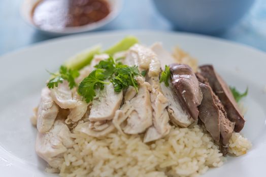 Rice steamed with chicken soup (hainanese chicken rice) with cucumber, liver and sauce for sale at Thai street food market or restaurant in Bangkok Thailand