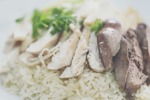 Rice steamed with chicken soup (hainanese chicken rice) with cucumber, liver and sauce for sale at Thai street food market or restaurant in Bangkok Thailand