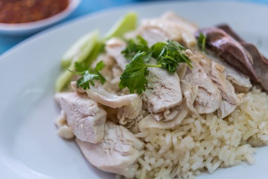 Rice steamed with chicken soup (hainanese chicken rice) with cucumber, liver and sauce for sale at Thai street food market or restaurant in Bangkok Thailand