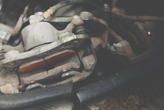 Car mechanic or serviceman checking a disc brake and asbestos brake pads it's a part of car use for stop the car for safety at front wheel this a used old part for change at car garage