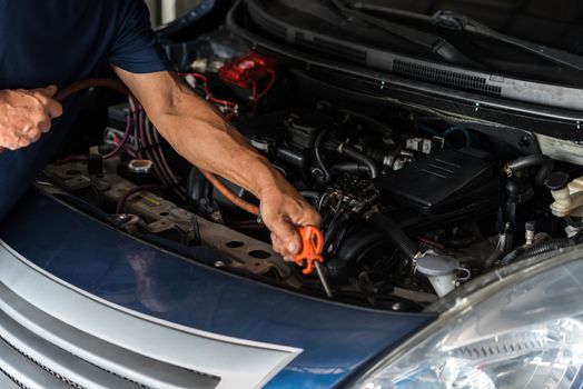 Car mechanic or serviceman cleaning the car engine after checking a car engine for fix and repair problem at car garage or repair shop