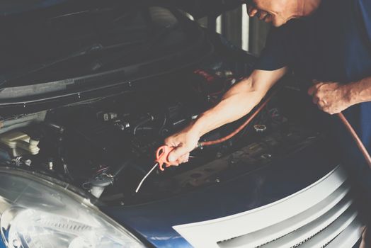 Car mechanic or serviceman cleaning the car engine after checking a car engine for fix and repair problem at car garage or repair shop