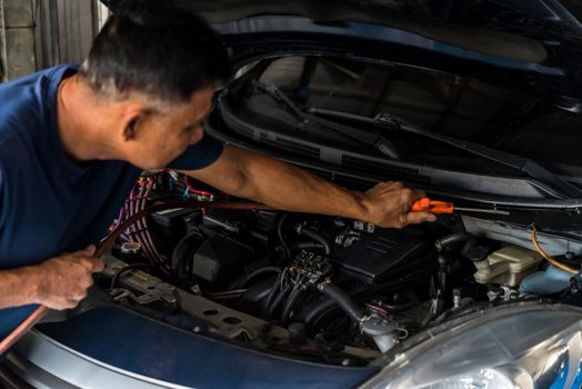 Car mechanic or serviceman cleaning the car engine after checking a car engine for fix and repair problem at car garage or repair shop