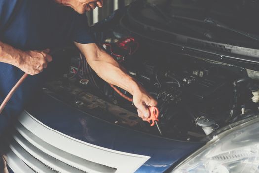 Car mechanic or serviceman cleaning the car engine after checking a car engine for fix and repair problem at car garage or repair shop