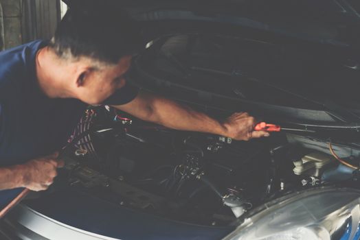 Car mechanic or serviceman cleaning the car engine after checking a car engine for fix and repair problem at car garage or repair shop