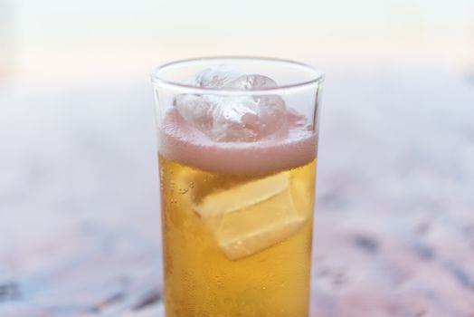 Fresh cold beer water in to beer glass with ice and froth in brewery pub or restaurant on a wood table