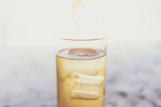 Fresh cold beer water in to beer glass with ice and froth in brewery pub or restaurant on a wood table