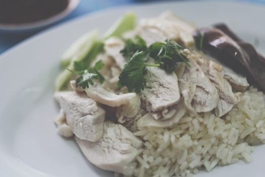 Rice steamed with chicken soup (hainanese chicken rice) with cucumber, liver and sauce for sale at Thai street food market or restaurant in Bangkok Thailand