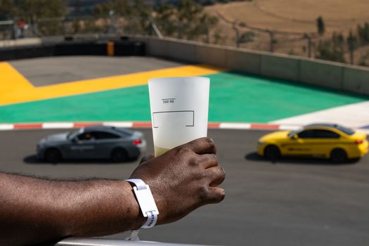 Man holding a drink glass at a motor race