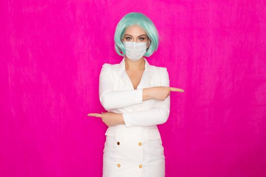 Beautiful young woman with short blue hair in a white business dress jacket with a medical mask posing on a pink background in the studio