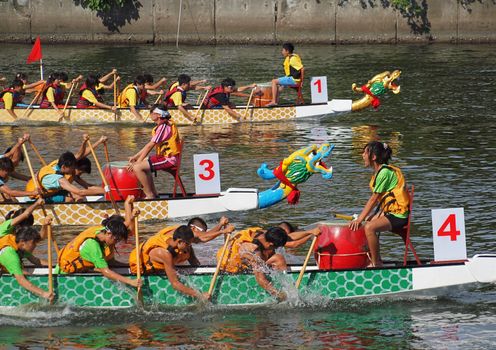 KAOHSIUNG, TAIWAN - JUNE 11: Three unidentified teams compete in the 2013 Dragon Boat Races on the Love River on June 11, 2013 in Kaohsiung