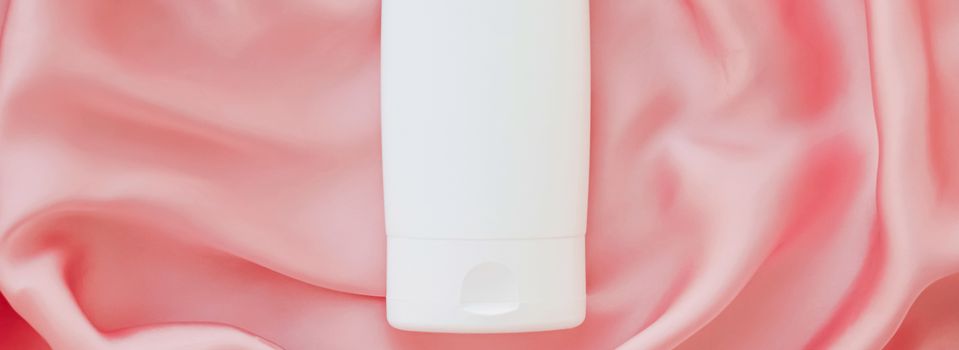 Blank label cosmetic container bottle as product mockup on pink silk background, hygiene and healthcare