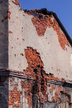 An abandoned brick building in a ruined state. Red brick wall