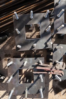 Construction site for a building with a steel structure. Plates with anchor bolts for mounting steel columns on a reinforced concrete foundation. Wrenches supported.