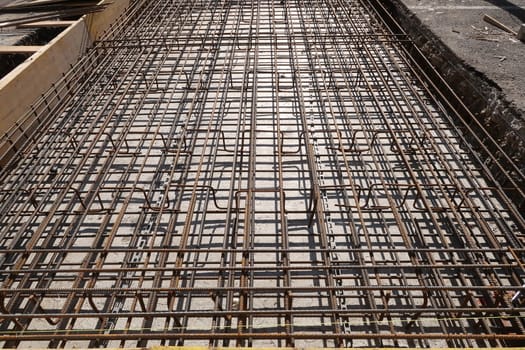 Dense texture of steel rods of a reinforced concrete foundation. Construction site.