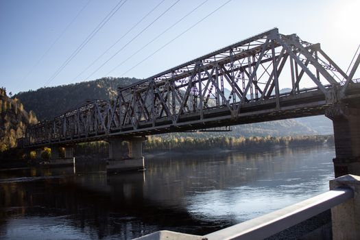 Railway bridge across the river in Russia. Travel through the mountains.