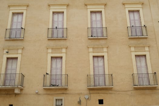 Facade of a Mediterranean palace with windows and balconies. Beige color plaster.