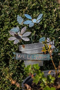 loseup of green basket with fresh flowers and welcome sign text written in black on wall near door