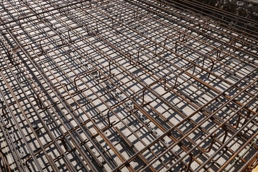 Dense texture of steel rods of a reinforced concrete foundation. Construction site.