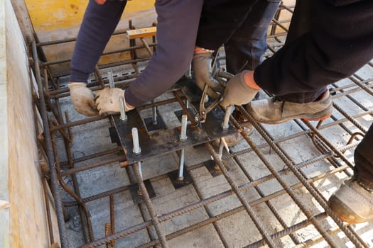 Milan, Lombardy, Italy. About 02/2020. Workers mount steel plates with anchor bolts for columns on a reinforced concrete foundation.