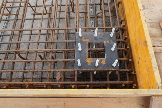 Construction site for a building with a steel structure. Plates with anchor bolts for mounting steel columns on a reinforced concrete foundation.