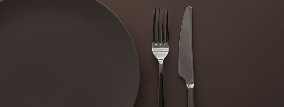 Empty plate and cutlery as mockup set on dark brown background, top tableware for chef table decor and menu branding design