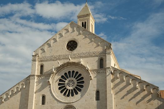 Facade of the Cathedral of San Sabino in Bari in limestone. Church with light stone walls with the blue sky background with clouds. Bari, Puglia, Italy.