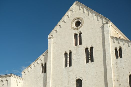  Façade of the church of San Nicola in Bari in limestone. Church with light stone walls with the blue sky background with clouds. Bari, Puglia, Italy. 