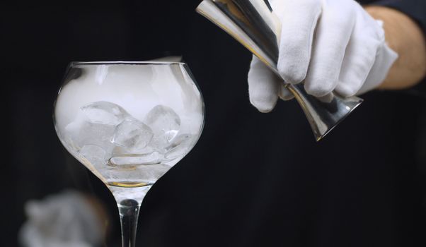 Close up drink with dry ice. Bartender preparing cocktail with dry ice in wine glass. The glass is wrapped in steam