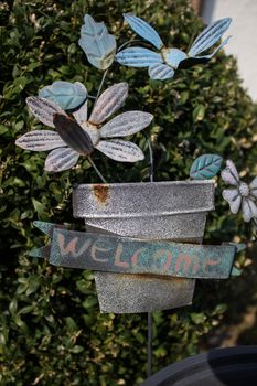 loseup of green basket with fresh flowers and welcome sign text written in black on wall near door