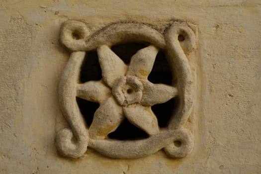 Matera, Italy. About 11/2019. Ventilation grid on the front of a house. Made of stone with a flower shape. Matera, Italy.