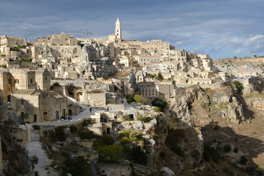 Panorama of the Sassi of Matera with houses in tuff stone. Church and bell tower at dawn with sky and clouds.