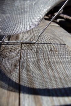 light through a metal sieve onto a wooden Board.