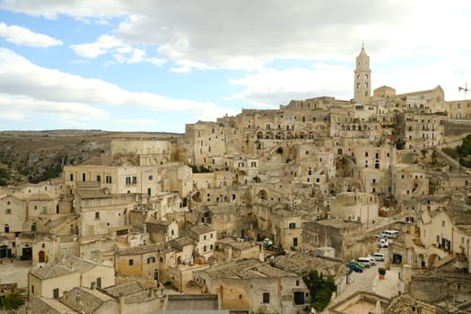 View of the city of Matera in Italy. Church with bell tower and houses built in beige tuff stone.