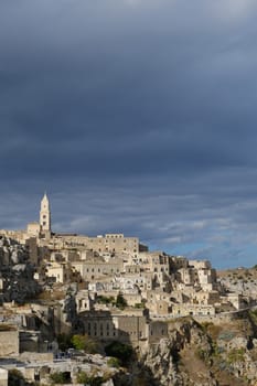 Panorama of the Sassi of Matera with houses in tuff stone. Church and bell tower at dawn with sky and clouds.