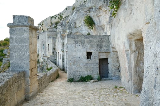 Road and facades of the Sassi of Matera. Doors and windows of ancient underground houses carved into the tuff rock.