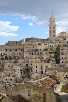 View of the city of Matera in Italy. Church with bell tower and houses built in beige tuff stone.