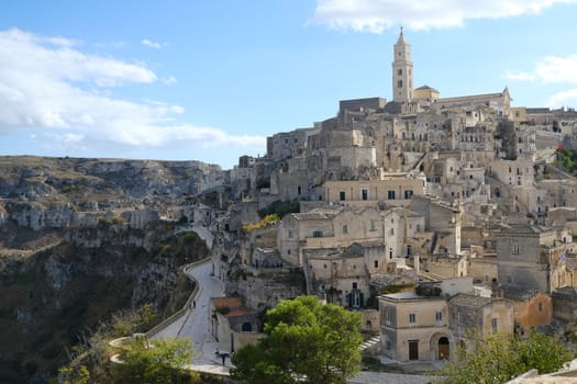 View of the city of Matera in Italy. Church with bell tower and houses built in beige tuff stone.