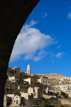 Panorama of the Sassi of Matera with houses in tuff stone. Church and bell tower at dawn with sky and clouds.